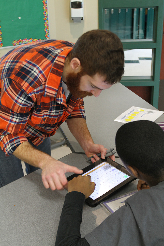Teacher helping student with iPad.