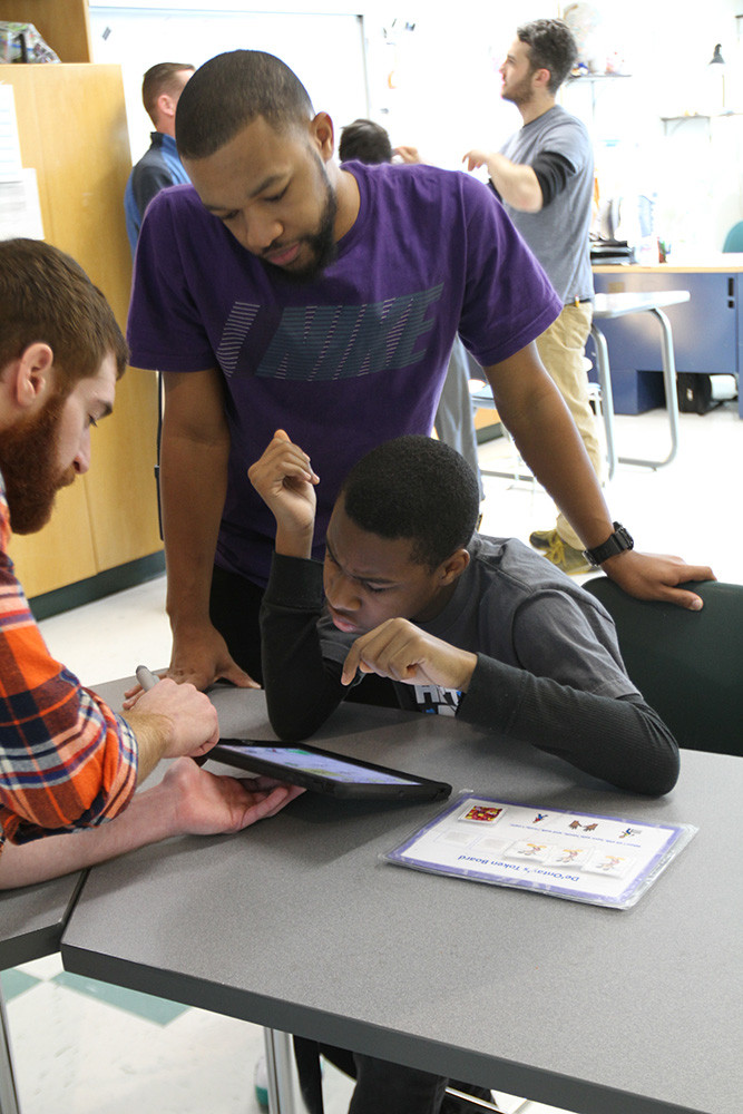 Teachers working with student on iPad.