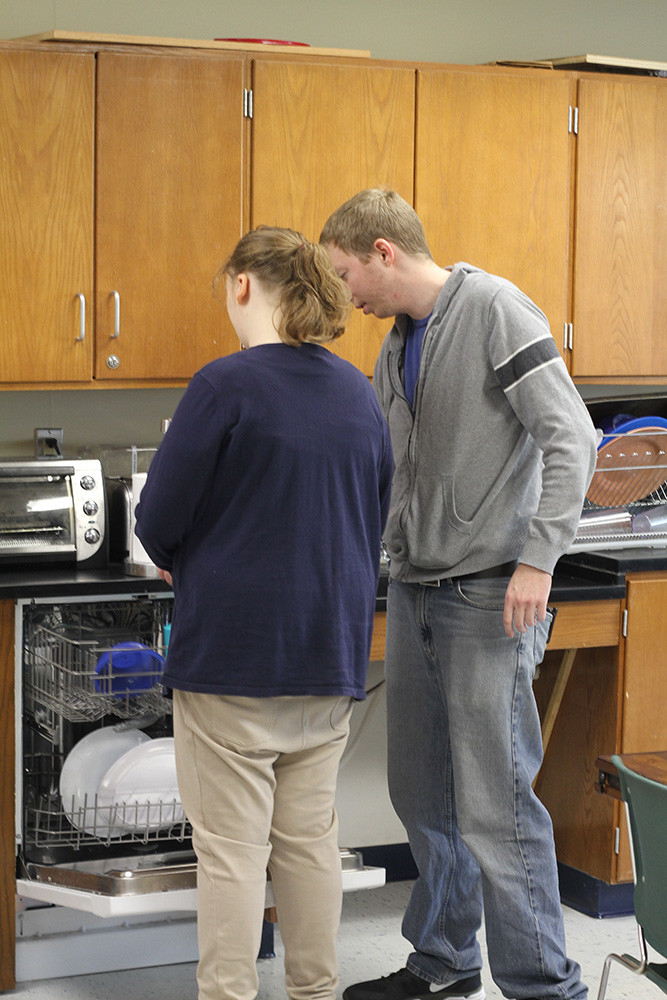 Teacher and student practicing life skills in kitchen setting.