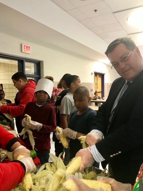 Mill Road students shucking corn with Assistant Executive Director Tim Howes
