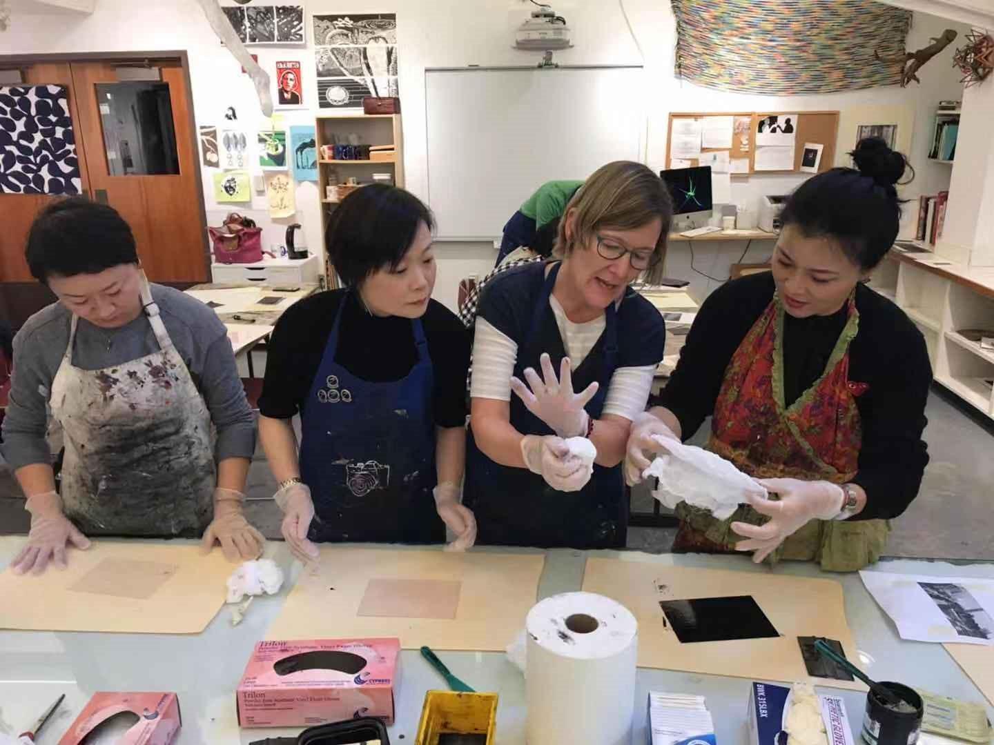 "The Visiting Scholars team wears paint-stained aprons as they work on art project at ECA school.”