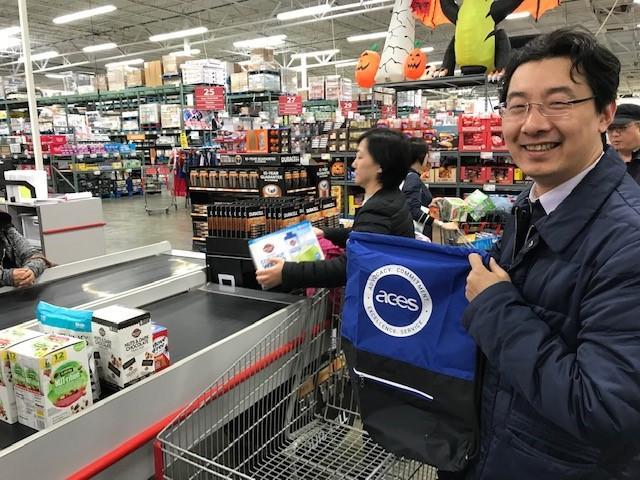 "Visiting Scholars poses for a photo, holding up an ACES branded backpack in a grocery store.”