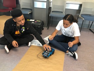 students sitting on floor with robotic car