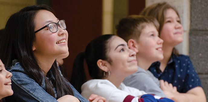 Several smiling young campers observe a lesson.