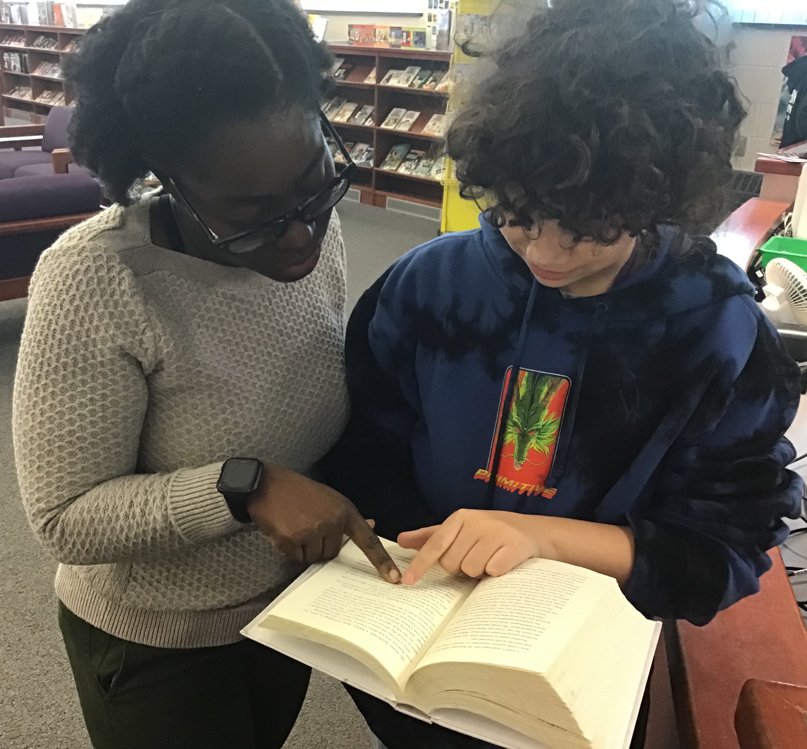 student and teacher looking at book