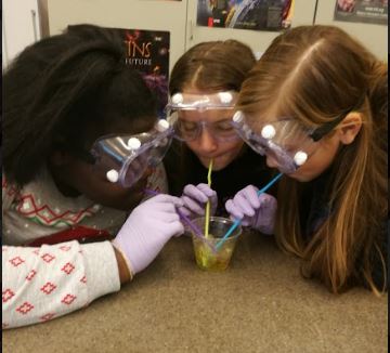 Students blow through straw into cup