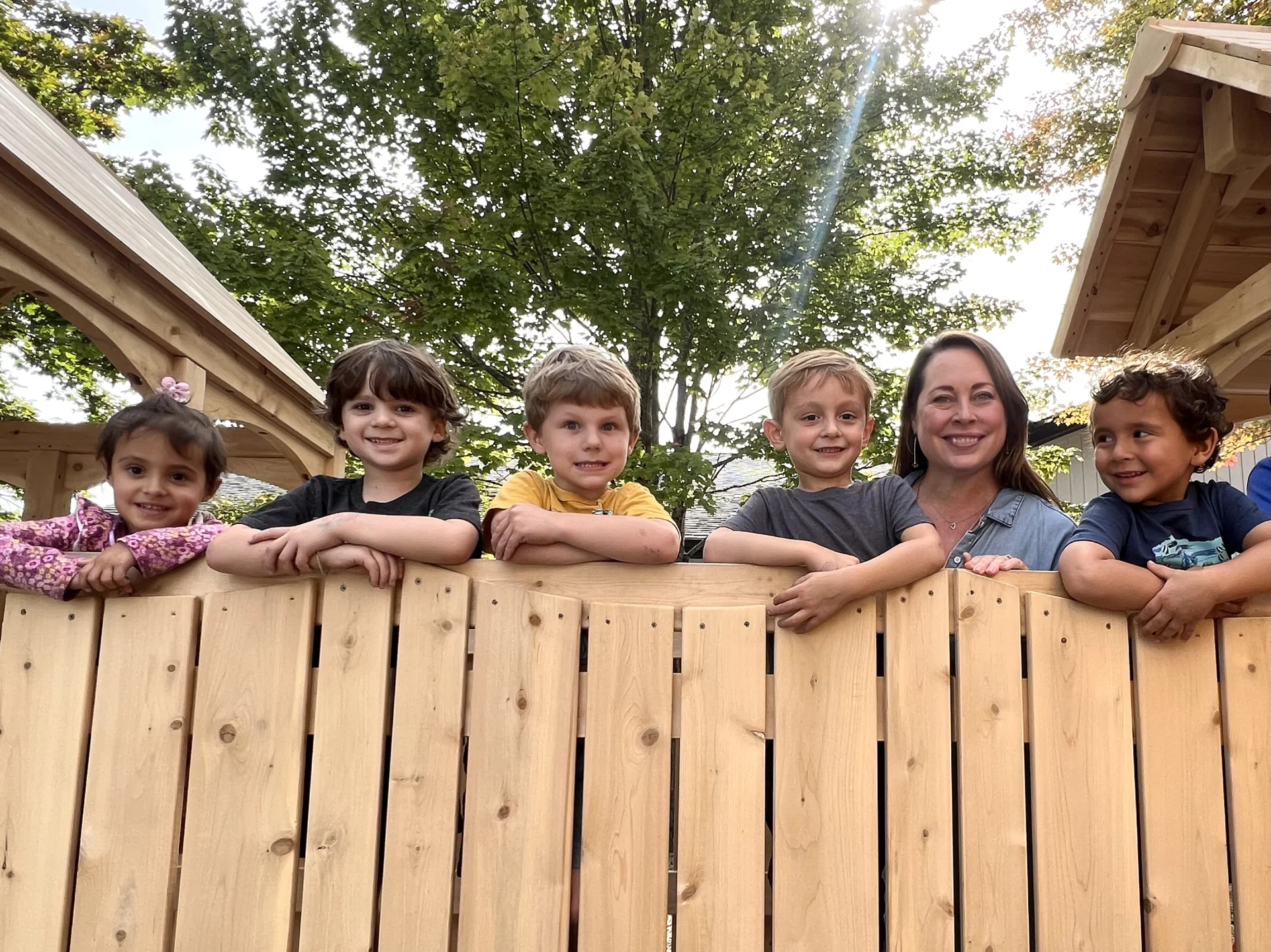 preschool students peaking over fence